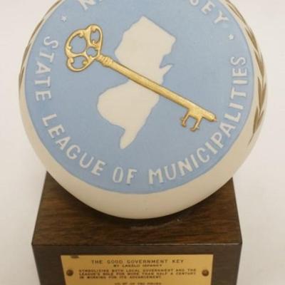 Sale Photo Thumbnail #117: 1117	LASZLO ISPANKY PORCELAIN COMMEMORATIVE NEW JERSEY GOOD GOVERNMENT KEY MOUNTED ON WALNUT BLOCK, APPROXIMATELY 8 IN

