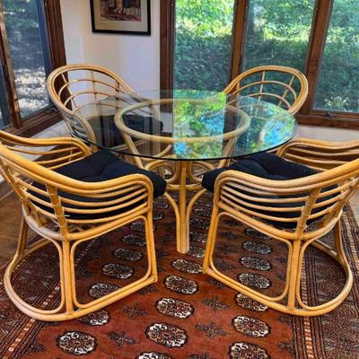 Oval Glass Top Dining Table with Rattan Base (48” x 26”) with four chairs. Table and chairs will be sold separately.