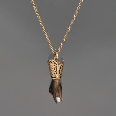 A VERY FINE VICTORIAN CARVED HAND PENDANT NECKLACE | Designed as a carved onyx hand with extended thumb and forefinger grasping a small...