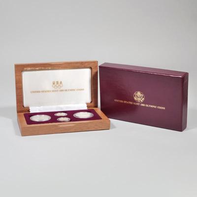 UNITED STATES 1988 OLYMPIC COINS | A four-coin set in a wooden presentation box, including 2 silver dollar coins (0.85 ozt) and 2 gold...