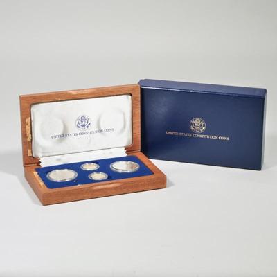UNITED STATES CONSTITUTION COINS SET | A four-coin set in a mahogany presentation box, including 2 1987 silver dollar coins (0.86 ozt),...