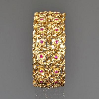 ITALIAN RUBY & 18k GOLD BRACELET |Hard yellow gold bangle bracelet with hinged opening, designed as two rows of gold flowers, each...