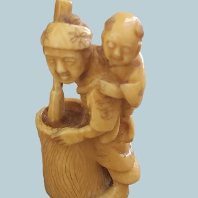 Sale Photo Thumbnail #60: Antique Japanese carved netsuke of a mother and child. Artist signed. With Himotoshi (two holes) used for the cord to attach the Netsuke to the obi. Measures 2 1/4". 
