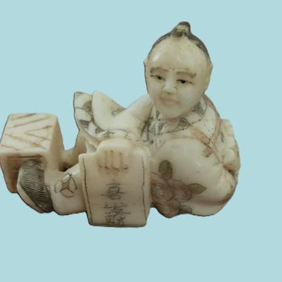 Sale Photo Thumbnail #53: Antique Japanese carved netsuke of a seated man with a box and the old numbers game.. Artist signed. With Himotoshi (two holes) used for the cord to attach the Netsuke to the obi. Measures 2 1/8".