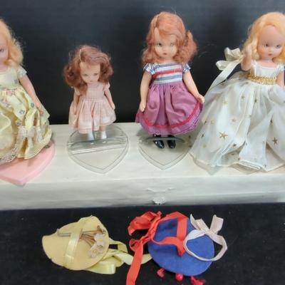 Collection of vintage dolls, likely Nancy Ann Storybook Dolls, arranged on Heart Shaped Doll Stands 