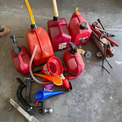 Assorted Gas Cans, Car Jack, Ball Hitch, And Assorted Funnels.