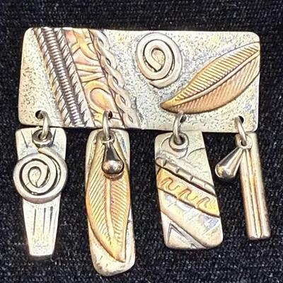Multi metal pendant featuring feather and spiral motifs