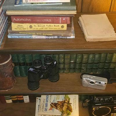 Vintage Bookshelf with Books, Binoculars, and Collectibles
