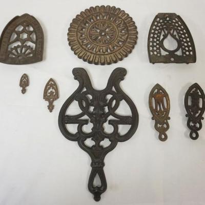 Sale Photo Thumbnail #101: 1101	GROUP OF ASSORTED ANTIQUE TRIVETS INCLUDING CAST IRON GRISWOLD, LARGEST APPROXIMATELY 12 IN X 7 IN X 1 IN
