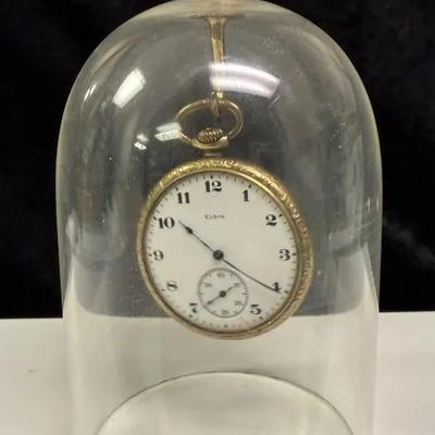 Elgin pocket watch displayed under a glass dome