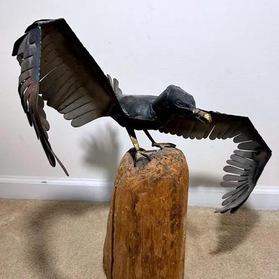Metal Bird Sculpture Mounted On Weathered Piling