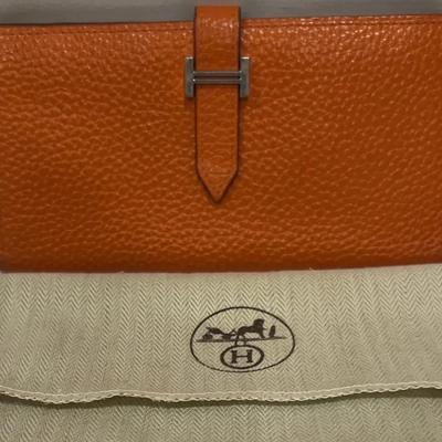 Hermès Bearn wallet in orange leather with an H-style clasp.