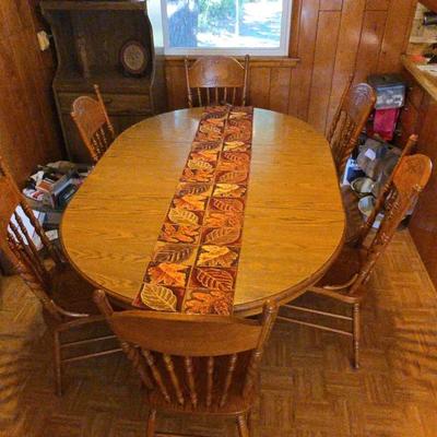 A Wooden Oval Dining Table With 6  Chairs And Fabric Runner 