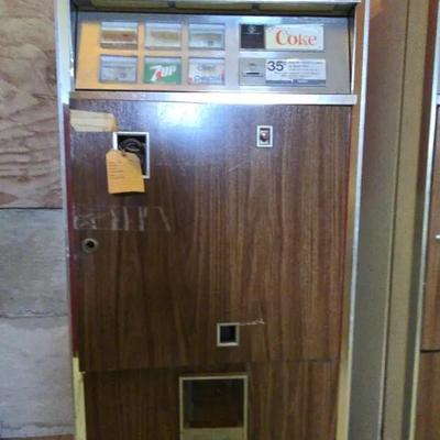 Classic mid-century Coca-Cola vending machine with woodgrain finish and chrome accents.
