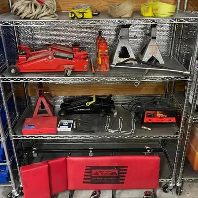 Automotive Tool Collection with Floor Jacks, Creeper, and EverStart Charger on Metal Shelving