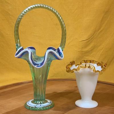 Fenton green glass basket with a double rung handle and a white vase
