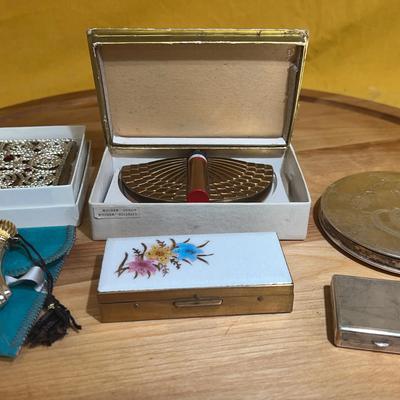 A collection of vintage vanity items including compacts and lipstick holder