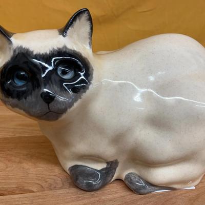A vintage ceramic Siamese cat figurine with blue glass eyes