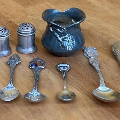 Collection of assorted silver-plated souvenir spoons, salt shakers, and pitcher