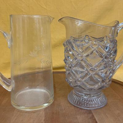A pair of vintage glass pitchers, one etched and one pressed glass