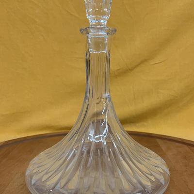 A clear crystal decanter with ribbed design and faceted stopper