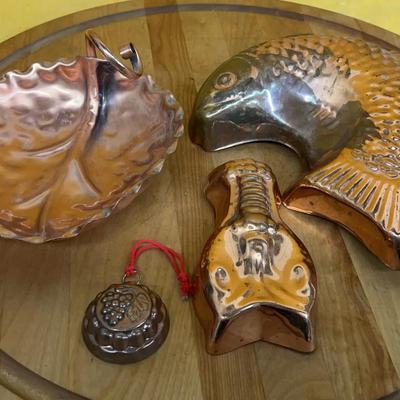 Collection of vintage copper molds including a fish, a lobster, leaf dish, and grape mold
