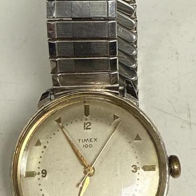 vintage gold-tone Timex 100 series manual-wind watch with a pie-pan dial and an expansion band