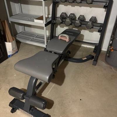 adjustable weight bench with a leg hold-down attachment and a two-tier dumbbell rack