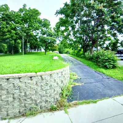 The driveway to the property is to the right of the stone wall