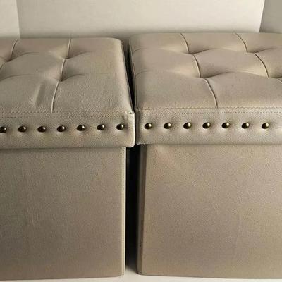 This is a beige faux leather tufted storage ottoman cube with gold-tone nailhead trim. 

