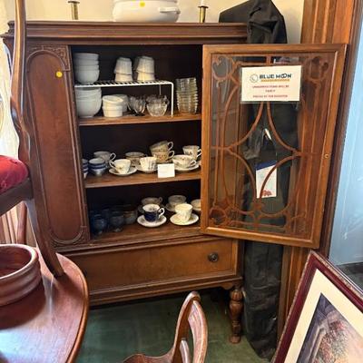 an antique wooden china cabinet with an inlaid glass door and a bottom drawer