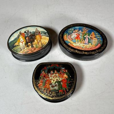 (3pc) Russian Painted Lacquer Boxes | Including two oval boxes and one half round box, all with figural scenes on the lids and red...