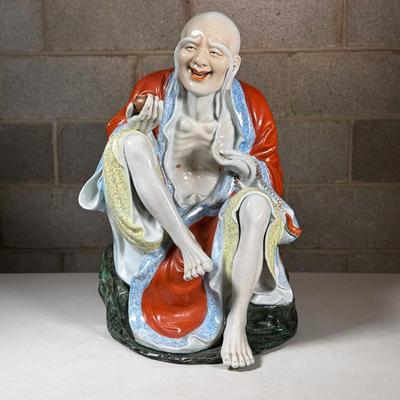 Chinese Porcelain Elder Figure | A laughing Luohan (or Buddhist immortal) seated and holding a cup or alms bowl, with colorful glaze and...