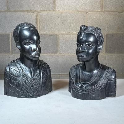 Pair African Carved Wood Busts | Hand-carved stylized male and female figures in a dark polished wood, with no apparent signature...