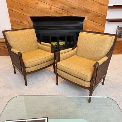 Pair Louis XVI-Style Cane Armchairs | Neoclassical style club chairs having carved wood square frames with cane sides and cushioned...