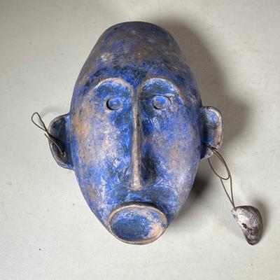 African Painted Pottery Mask | Mask with elongated face, having a blue pigmented surface with wire attachments and a shell suspended at...