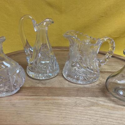 Collection of three glass pitchers and one glass cruet with stopper
