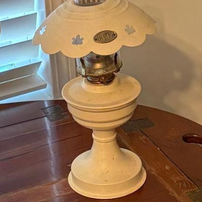 Vintage white table lamp appears cast or painted metal, with decorative scalloped shade and floral cutout details.
