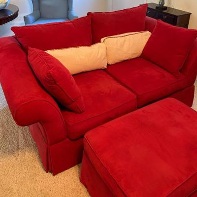 Red upholstered loveseat with ottoman, appears modern, plush seating set