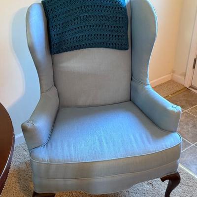 Upholstered wingback armchair, light blue fabric, traditional style, appears wood legs
