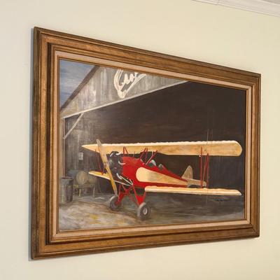 Framed airplane artwork, aviation-themed print depicting vintage biplane in hangar.