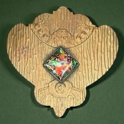 Gold tone brooch with a multi color central stone