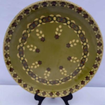 This is a vintage Bulgarian glazed ceramic plate with a hand-painted floral design. 