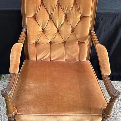 Vintage button-back armchair with carved wooden details and gold velvet upholstery.