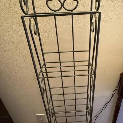 A tall metal floor magazine rack with decorative scrollwork—likely late 20th century, steel or wroug