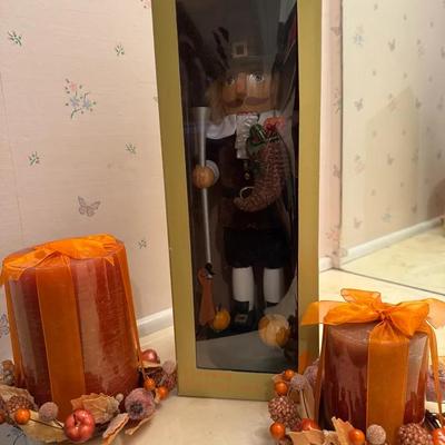 A Pilgrim / Harvest Nutcracker–style figure, paired with fall-themed pillar candles and décor rings.