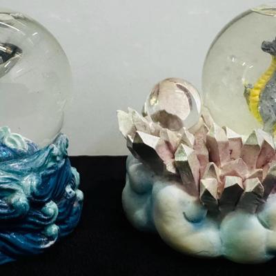 Pair of decorative snow globes featuring fantasy and marine themes.