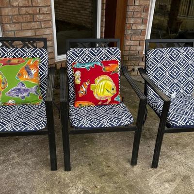 Three metal patio chairs with cushions and throw pillows 