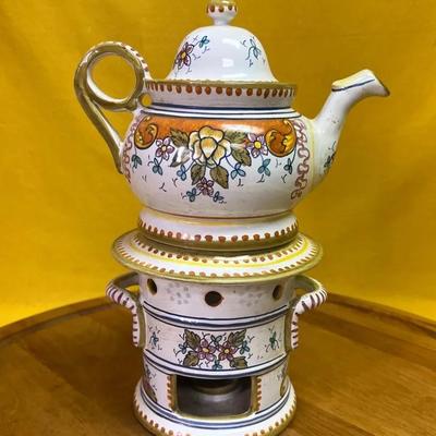 A hand-painted porcelain tisanière with a floral pattern and warming stand