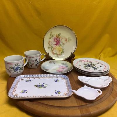 A collection of hand-painted porcelain mugs, plates, and serving dishes